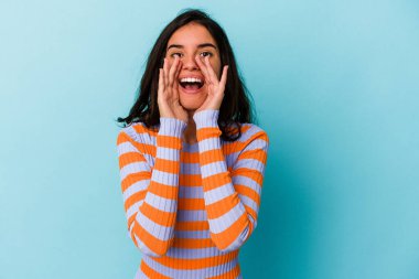 Kafkasyalı genç bir kadın mavi arka planda izole edilmiş. Dedikodu yapıyor, bir şeyleri bildiriyor..