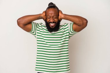 Pembe arka planda sakallı, kulakları elleri kulaklarıyla kapalı, yüksek ses duymamaya çalışan Afrikalı Amerikalı bir adam..