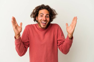 Beyaz arka planda izole genç beyaz adam hoş bir sürpriz alıyor, heyecanlı ve el kaldırıyor..