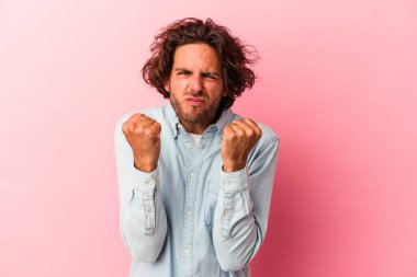 Pembe fırında izole edilmiş genç beyaz bir adam kameraya yumruğunu gösteriyor, agresif bir yüz ifadesi..
