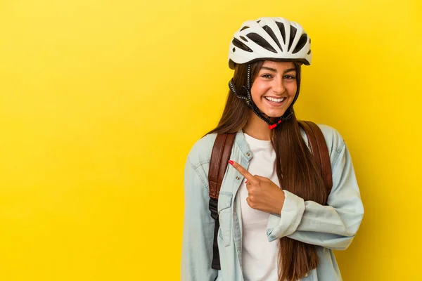 若いです学生Caucasian女性を身に着けています自転車ヘルメット黄色の背景笑顔と脇を指して 空白のスペースで何かを示します — ストック写真