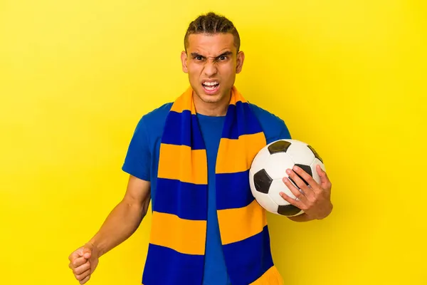 Młody Wenezuelczyk Człowiek Oglądać Piłka Nożna Odizolowany Żółtym Tle Krzyczy — Zdjęcie stockowe
