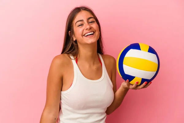年轻的高加索女人拿着一个被粉色背景隔开的排球球 开心地笑着 — 图库照片