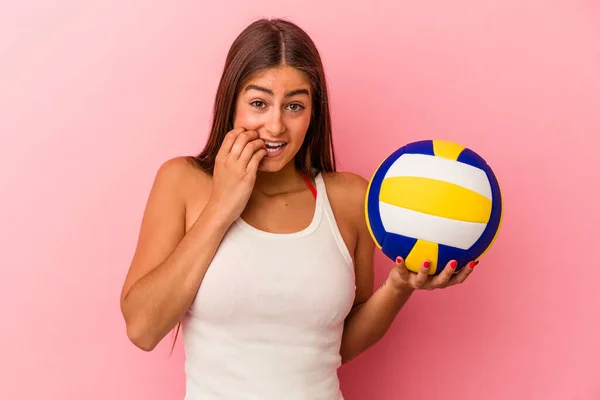 Молодая Кавказская Женщина Держащая Волейбольный Мяч Розовом Фоне Кусает Ногти — стоковое фото