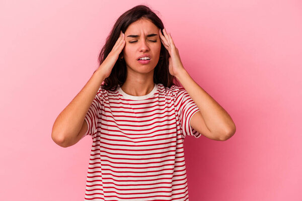 Young caucasian woman isolated on pink background having a head ache, touching front of the face.