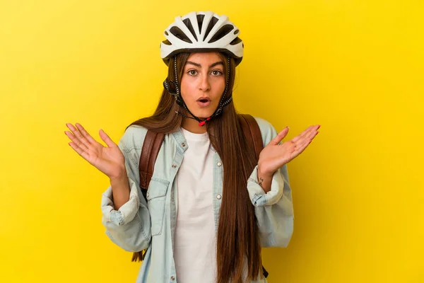 若いです学生Caucasian女性身に着けていますAバイクヘルメット隔離上の黄色の背景驚きとショック — ストック写真