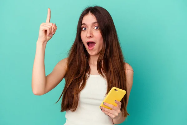 Joven Mujer Caucásica Sosteniendo Teléfono Móvil Aislado Sobre Fondo Azul — Foto de Stock