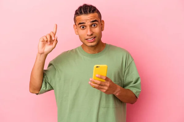 Młody Wenezuelczyk Trzymający Telefon Komórkowy Różowym Tle Pomysłem Inspiracją — Zdjęcie stockowe