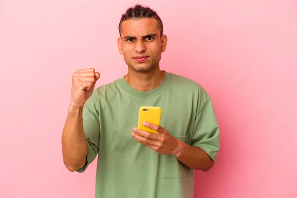 Młody Wenezuelczyk Trzymający Telefon Komórkowy Odizolowany Różowym Tle Pokazujący Pięść — Zdjęcie stockowe