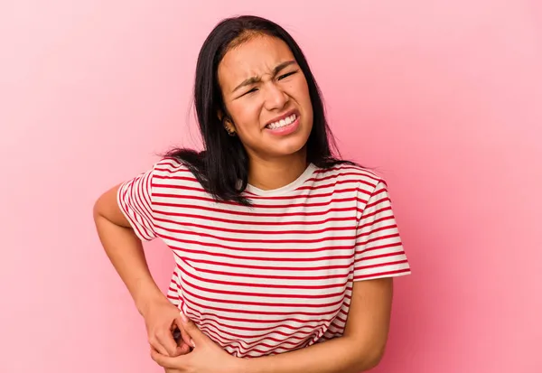 Genç Venezuelalı kadın pembe arka planda izole edilmiş karaciğer ağrısı, mide ağrısı var..