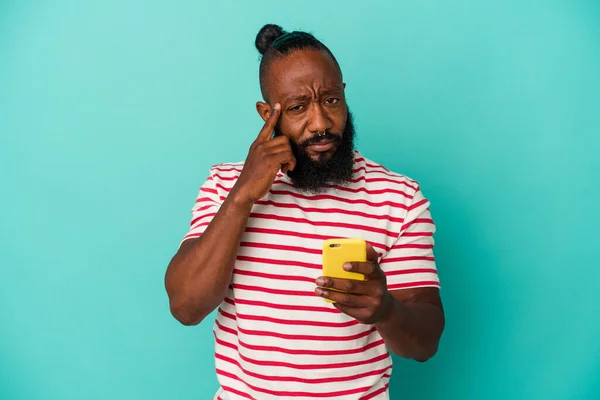 非洲裔美国人手持一部蓝色背景的手机 手拿着手指 思考着 专注于一项任务 — 图库照片