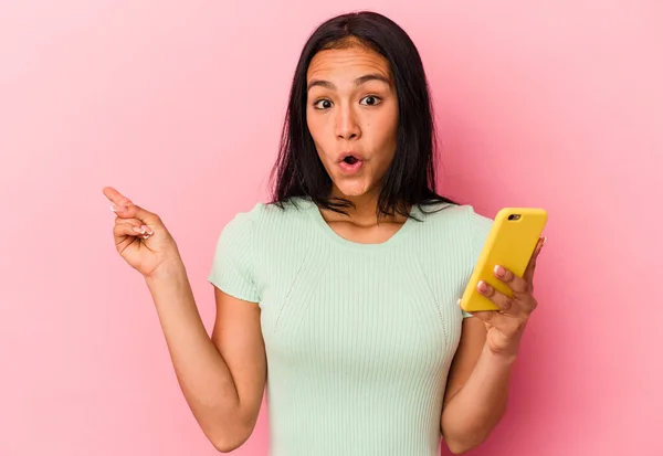 Mladá Venezuelská Žena Drží Mobilní Telefon Izolovaný Růžovém Pozadí Ukazuje — Stock fotografie