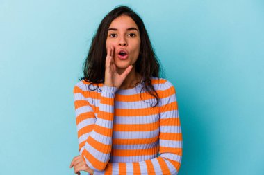 Mavi arka planda izole edilmiş genç beyaz kadın gizli bir sıcak fren haberi veriyor ve yana bakıyor.