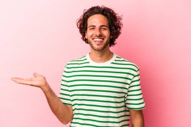 Pembe fırında izole edilmiş genç beyaz bir adam bir palmiye üzerinde fotokopi alanı ve belinde başka bir el tutuyor..