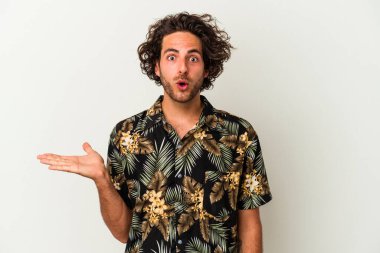 Beyaz arka planda izole edilmiş genç beyaz adam, avuç içi fotokopi alanını elinde tutmaktan etkilenmiş..