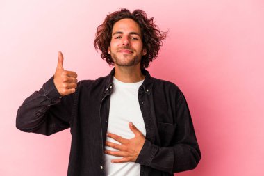 Pembe fırında izole edilmiş genç beyaz adam karnına dokunuyor, nazikçe gülümsüyor, yemek yiyor ve tatmin oluyor..