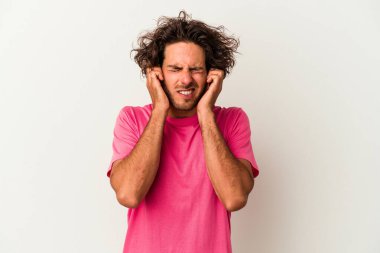 Beyaz arka planda izole edilmiş genç beyaz bir adam kulaklarını elleriyle kapatıyor..