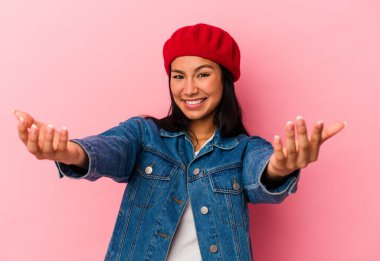 Genç Venezuelalı kadın pembe arka planda izole edilmiş hoş bir ifade sergiliyor..