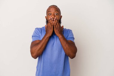 Pembe arka planda sakallı Afrikalı Amerikalı adam elleriyle ağzını kapatırken şok oldu..