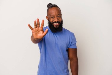 Pembe arka planda sakallı Afrikalı Amerikalı adam gülümseyerek beş numarayı parmaklarıyla gösteriyor..