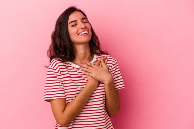 Pembe arka planda soyutlanmış beyaz bir kadın gülüyor, elini yüreğine koyuyor, mutluluk kavramını koruyor..