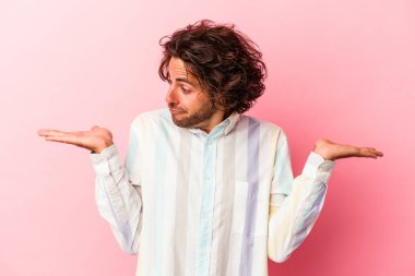 Kafkasyalı genç bir adam pembe fırında izole edilmiş. Kafası karışmış ve omuz silkiyor. Kopya alanını tutmak için..