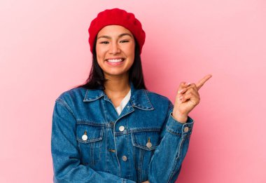 Genç Venezuelalı bir kadın pembe arka planda izole edilmiş, mutlu bir şekilde işaret parmağıyla işaret ediyor..