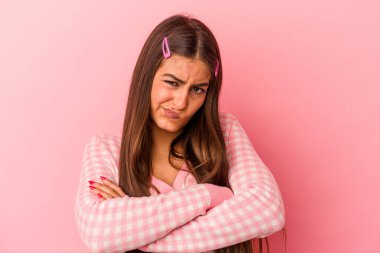 Pembe arka planda soyutlanmış beyaz bir kadın hoşnutsuzca kaşlarını çatmış, kollarını kavuşturmuş..