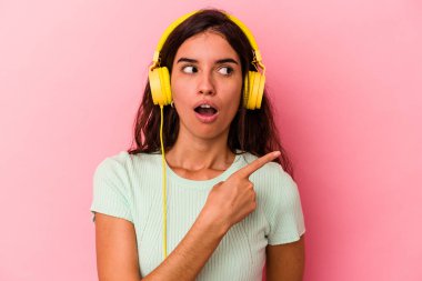 Pembe arka planda izole edilmiş müzik dinleyen beyaz bir kadın.