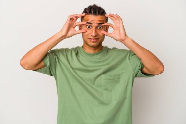 Genç Venezuelalı bir adam beyaz arka planda izole edilmiş bir şekilde gözlerini açık tutarak bir başarı fırsatı arıyor..