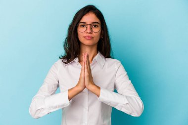 Kafkasyalı genç kadın mavi arka planda izole edilmiş dua ediyor, bağlılık gösteriyor, dindar biri ilahi ilham arıyor..