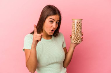 Pembe arka planda izole edilmiş nohut kavanozu tutan beyaz bir kadın bir fikri var, ilham verici bir kavram..