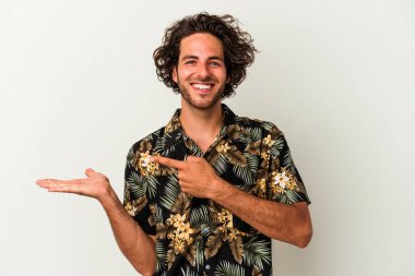 Beyaz arka planda izole edilmiş genç beyaz bir adam, palmiye üzerinde bir fotokopi alanı tutarken heyecanlı..