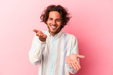 Pembe fırında izole edilmiş genç beyaz adam kollarıyla ölçek yapar, mutlu ve kendinden emin hisseder..