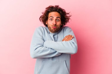 Pembe fırında izole edilmiş genç beyaz adam omuzlarını silkeliyor ve gözleri açık..