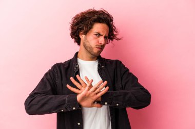 Pembe fırında izole edilmiş genç beyaz adam inkar jesti yapıyor.