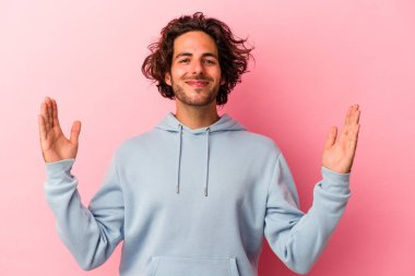 Kafkasyalı genç adam pembe fırında izole edilmiş. Elinde parmakları olan küçük bir şey tutuyor, gülümsüyor ve kendinden emin..