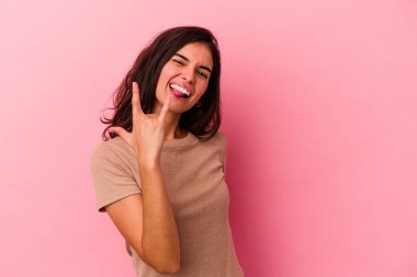 Pembe arka planda izole edilmiş genç beyaz kadın parmaklarıyla taş hareketi gösteriyor.