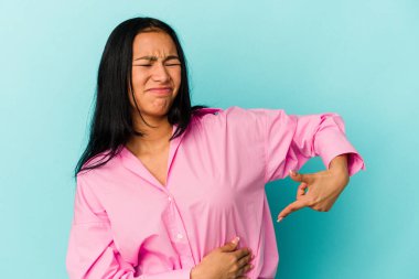 Genç Venezuelalı bir kadın mavi arka planda karaciğer ağrısı ve mide ağrısı çekiyor..