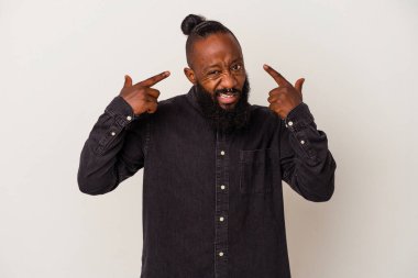 Pembe arka planda sakallı Afrikalı Amerikalı bir adam işaret parmağıyla hayal kırıklığı jesti yapıyor..