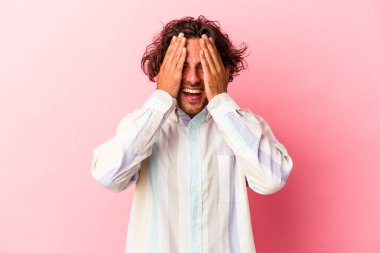 Pembe fırında izole edilmiş genç beyaz adam yüzünün yarısını palmiye ile örterek eğleniyor..