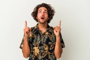 Beyaz arka planda izole edilmiş genç beyaz adam ağzı açık bir şekilde üst tarafı işaret ediyor..