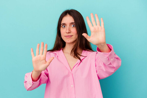 Young caucasian woman isolated on blue background being shocked due to an imminent danger