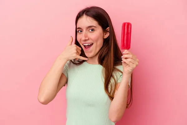 青い背景に隔離されたアイスクリームを持っている若い白人女性は 指で携帯電話の呼び出しジェスチャーを示しています — ストック写真