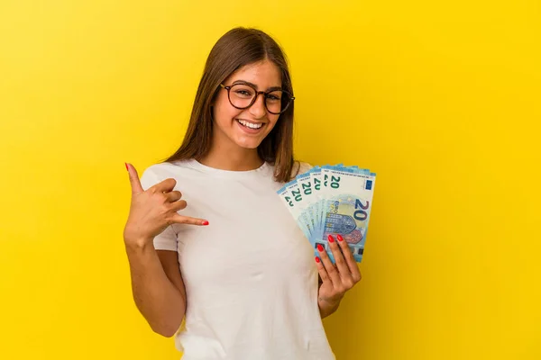 Young Caucasian Woman Holding Bills Isolated Yellow Background Showing Mobile — Stock Photo, Image