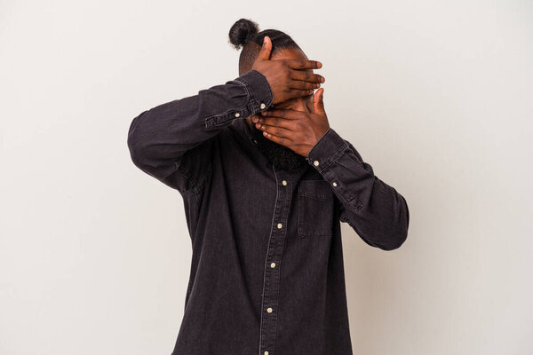 African american man with beard isolated on pink background blink at the camera through fingers, embarrassed covering face.