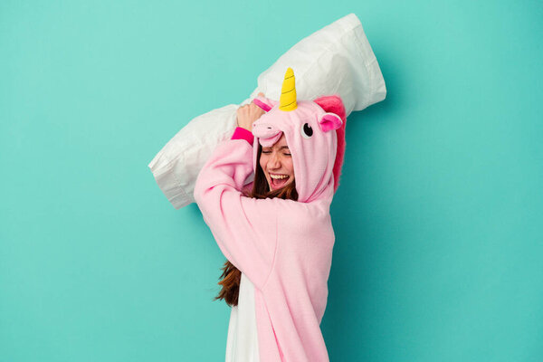 Young caucasian woman wearing a unicorn pajama isolated on blue background