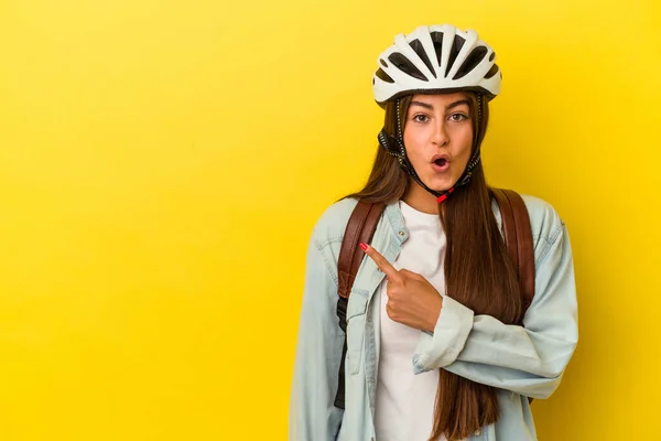 若いです学生Caucasian女性身に着けていますAバイクヘルメット隔離上の黄色の背景を指す側 — ストック写真