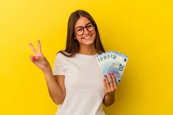 Mladá Běloška Drží Bankovky Izolované Žlutém Pozadí Ukazující Číslo Dvě — Stock fotografie