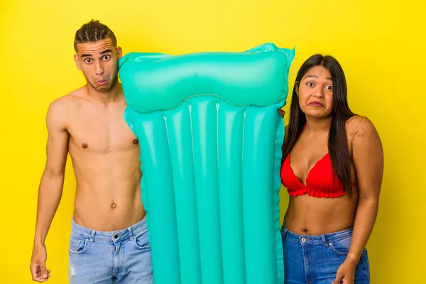 Jovem Casal Latino Segurando Colchão Isolado Fundo Amarelo Encolhe Ombros — Fotografia de Stock